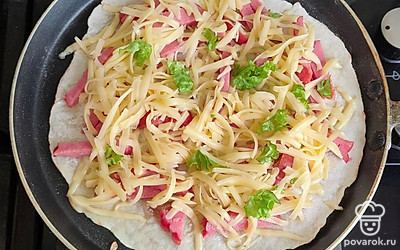 Разогрейте сковороду, обжарьте пласт теста на медленном огне с двух сторон. На один пласт поставьте сыр, колбасу и зелень и закройте другим пластом. Обжаривайте в течение минуты с каждой стороны.