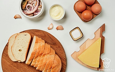 Батон нарежьте на ломтики толщиной 1 см. Куриные яйца помойте, отварите вкрутую, почистите и натрите на терке. Сыр натрите на терке. Чеснок почистите и пропустите через пресс. С морского коктейля слейте рассол, мелко порежьте. Укроп помойте и обсушите. Разогрейте духовку до 200 градусов.