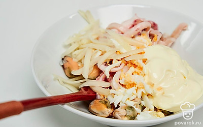 Приготовьте начинку. Соедините в миске яйца, сыр, морской коктейль, чеснок, соль и майонез. Хорошо перемешайте.