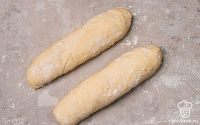 Приступите к формовке. Выложите тесто на рабочую поверхность, предварительно присыпанную мукой, разделите пополам. Расплющите, заверните края в центр, формируя прямоугольники. Оставьте на 10 минут. Затем из каждой части сформируйте рулет, заготовку немного растяните, равномерно отрегулируйте толщину изделия. Оставьте на 40 минут.