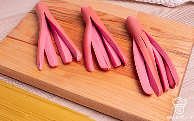 Сосиски положите на разделочную доску и разрежьте на 4 части, не доходя до конца 3-4 см.