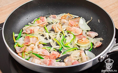 Разогрейте сковороду. Налейте масло. Обжарьте лук. На большом огне обжарьте бекон с перцем.