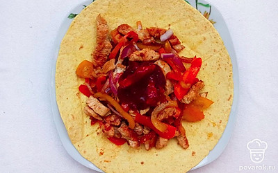 В обжаренное мясо с овощами добавьте томатный соус, соль и перец, томите блюдо под крышкой еще 10 минут, после чего выложите ысо с овощами на тортилью и подавайте к столу.