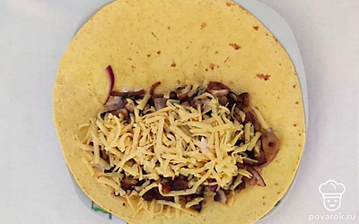 На тарелке разложите тортилью, на одну половину выложите половину сыра, поверх лук и грибы, засыпьте оставшимся сыром. Сложите по полам, прожарьте на сковороде 2-3 минуты с каждой стороны.