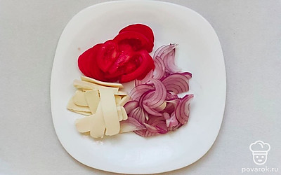 Подготовьте начинку, для этого в отдельную емкость нарежьте томаты полукольцами и также лук, для того чтобы сыр выглядел аппетитным, нарежьте его тонкими пластинками.