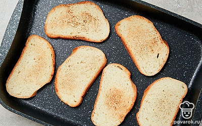 Приготовьте тосты. Противень установите в духовке на верхний отдел и подсушите хлебные ломтики с одной стороны около 5 минут. Когда верхняя часть зарумянится, переверните кусочки и готовьте столько же времени.