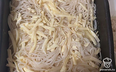 На противень первым слоем выкладываем половину отваренного спагетти. Сверху посыпаем тертым сыром.