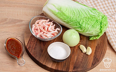 Ополосните тушку кальмара, снимите с нее тонкую пленочку. Нарежьте тонкими полосками. С кочана пекинского салата снимите вялые листья, промойте его под струей воды. Лук и чеснок очистите от шелухи. Подготовьте соус аджики и соль.