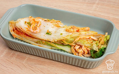 Возьмите чистую форму. Заправкой из аджики, кальмара, лука и чеснока обмажьте капусту. Уложите в форму и отправляйте мариноваться в холодильник на сутки. Когда капуста замаринуется, она станет упругой.