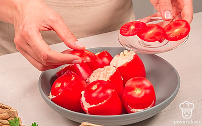 Приготовьте закуску из помидоров с чесноком. Разложите помидоры на блюде. Аккуратно чайной ложкой равномерно разложите по ним начинку. По желанию каждый помидор можно накрыть срезанной верхушкой, чтобы получилась импровизированная "крышка".