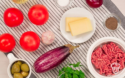 Помойте помидоры и баклажаны. Почистите лук и зубчики чеснока. Соберите мясорубку, достаньте форму для запекания или глубокий противень. Зелень петрушки и базилик сполосните, стряхните лишнюю воду. Петрушку мелко нарубите, базилик разберите на отдельные листочки. Натрите сыр на мелкой терке.