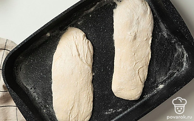 Испеките багеты-чиабатты. Противень застелите пергаментом, посыпьте мукой, аккуратно выложите на него заготовки. В другую форму для запекания налейте кипяток. Выпекайте багеты в течение 10 минут с паром. Затем уберите форму с водой и выпекайте хлеб еще 20 минут.