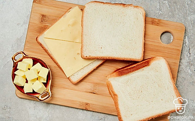 Подготовьте тосты. Положите на ломтик хлеба кусок сыра и масла, сверху накройте его другим кусочком. Должно получиться три тоста.
