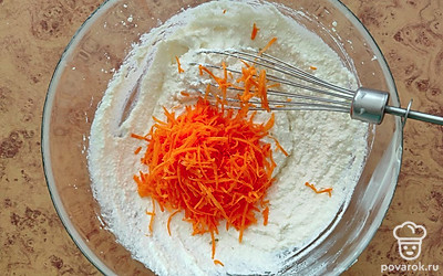 Морковь очистите от кожуры и натрите на мелкой терке. Всыпьте ее в тесто и перемешайте. Через сито добавьте муку и еще раз перемешайте. 