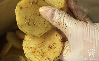 Картошку нарезаем слайсами не слишком тонко. Вливаем растительное масло, всыпаем 1 столовую ложку соли, паприку, 1 чайную ложку перца и хмели-сунели.