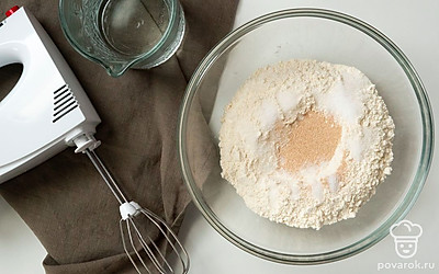 Замесите тесто. Соедините воду и муку. Оставьте смесь на 45 минут, чтобы мука поглотила влагу. Добавьте соль, дрожжи. Размешивайте 8 минут. Лучше это делать с помощью миксера со специальным насадками для теста. Дайте постоять 20 минут.