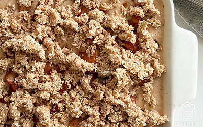 Измельчите овсяные хлопья в кофемолке. Перетрите получившуюся муку с маслом в крошку. Посыпьте этой крошкой запеканку и отправьте в разогретую до 180 градусов духовку на 25-30 минут.