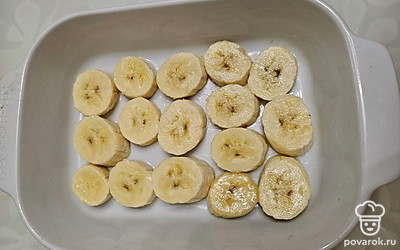 Банан очистите от кожуры и нарежьте слайсами. Форму для запекания смажьте небольшим количеством масла. Выложите банан на дно.