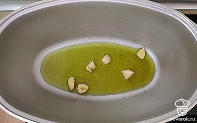 На дно казана налейте немного растительного масла и разогрейте. Добавьте 2 зубчика чеснока.