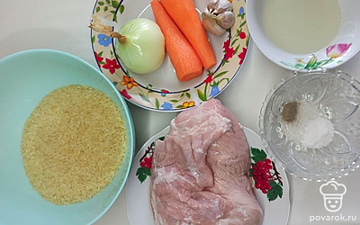 Подготавливайте и отвесьте все необходимые продукты для быстрого плова в сковороде. Очищайте лук и морковь, чеснок очищайте только от верхнего слоя. С мясо свинины срезайте лишний жир и прожилки.