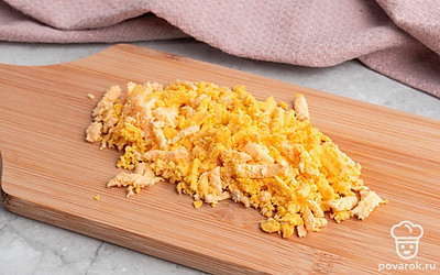 Вынутый желток и мелко покрошите его в отдельную миску. Натрите чеснок и сыр на терке.