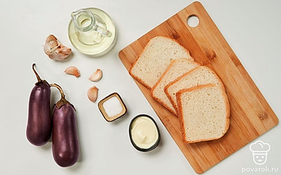 Предварительно помойте баклажан, зелень и очистите чеснок от шелухи. Отделите листочки петрушки от стеблей для украшения. Приготовьте противень и сковороду. Разогрейте духовку до 180 градусов.