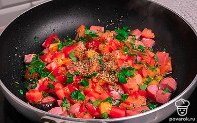 Затем добавьте порезанные помидоры и мелко порезанную зелень. Затем посыпьте специями орегано. Хорошо перемешайте и оставьте тушиться.
