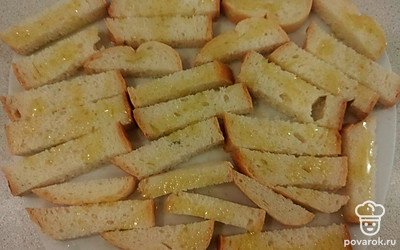 Хорошо разогрейте сковороду. Нарежьте хлеб длинными брусочками, полейте их половиной подготовленного оливкового масла и поджарьте на среднем огне, до румяной корочки.