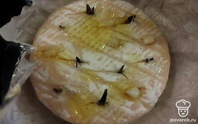 Острым ножом разрежьте (не глубоко) верхнюю корочку сыра, образуя своеобразную «решетку». А теперь в разрезы произвольно воткните нарезанный кружочками чеснок и листики розмарина, полейте сыр оставшимся оливковым маслом и лимонным соком.