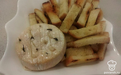 На большое, плоское блюдо, в центр поставьте чесночно-розмариновый, расплавленный камамбер, посыпьте его грецкими орехами. Рядом выложите гренки. Подавайте блюдо горячим с розовым вином.