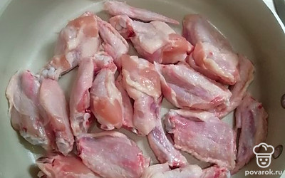 Крылышки разрезать на части. В глубокий сотейник налить растительное масло. Выложить крылышки. 