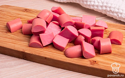 Сосиски очистите от целлофана. Разрежьте сначала пополам, затем каждую половинку на небольшие полукружочки. Лук очистите от кожуры и нарежьте полукольцами.