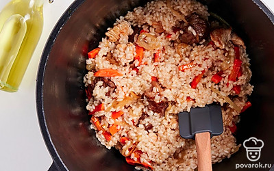 Приготовьте плов. Разровняйте обжарку ложкой или лопаткой, сверху распределите рис. Приправьте блюдо солью, красным и черным перцем. Налейте в казан кипящей воды столько, чтобы она покрыла рис на 2 см. Томите плов под крышкой на медленном огне 40 минут. Готовое блюдо хорошо перемешайте.