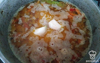 Влейте в казан 2 стакана воды, всыпьте специи, соль и перец по вкусу. Дайте закипеть, затем всыпьте рис и чеснок и варите на медленном огне до готовности.