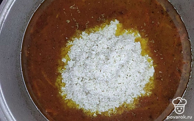 Всыпьте в казан промытый рис, налейте воду, вставьте целую головку чеснока. Накройте казан крышкой и томите плов на минимальном огне в течение 30-40 минут.