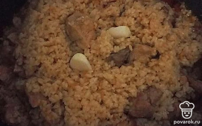 Собрать рис к середине, вложить чеснок и оставить так еще на 30 минут на самом слабом огне.