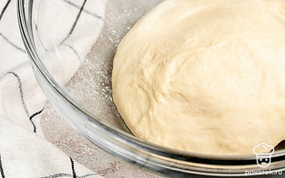 Замесите тесто для багетов. Порциями добавляйте к опаре муку и тщательно вымешивайте тесто. Укройте тесто полотенцем и уберите в теплое место на 90 минут.