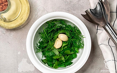 Приготовьте зеленую прослойку. В чашу блендера положите укроп, петрушку, чеснок и растительное масло. Перебейте все блендером в течение 3 минут.