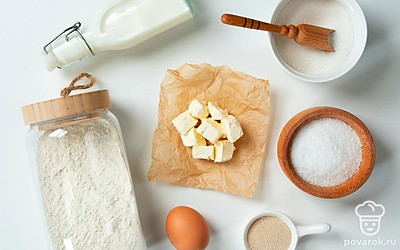 Молоко перелейте в отдельную миску, подогрейте до 40 градусов и добавьте в него сливочное масло. Просейте муку. Приготовьте пищевую пленку или полотенце, застелите противень пергаментной бумагой. Разогрейте духовку до 180 градусов.