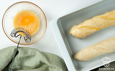 Поставьте багет запекаться. Яйцо взбейте, после чего смажьте им всю поверхность будущего багета, чтобы на нем образовалась румяная корочка. Противень поставьте в духовку на 20-25 минут при температуре 180 градусов.