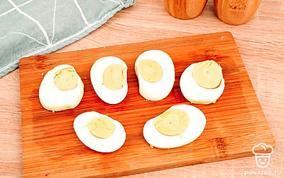 Нарежьте куриные яйца, сваренные вкрутую, на половинки.