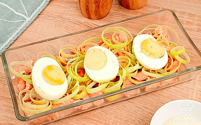 Выложите на рыбу лук-порей и нарезанные яйца.