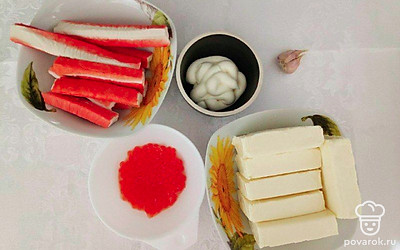 Разморозьте и распакуйте от оболочки крабовые палочки. Распакуйте плавленый сырок. Чеснок очистите и помойте. Зеленый лук помойте и обсушите.