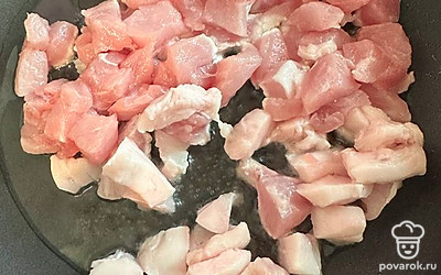 В сковороду наливаем растительное масло и добавляем жир. Выкладываем кубиками нарезанное мясо индейки.