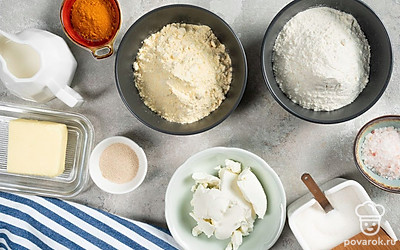 Приготовьте ковш, кастрюлю, пару глубоких мисок, противень и тарелку для подачи. Также понадобятся пергамент и полотенце. Нагрейте молоко с маслом, пока масло не растает. За 20 минут до выпечки разогрейте духовку до 190 градусов. Промойте и просушите зелень петрушки, мелко нарежьте.