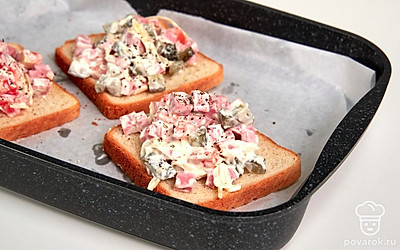 Сделайте тосты. Ломтики хлеба положите на противень, застеленный пергаментной бумагой. Сверху на каждый кусочек намажьте начинку. Отправьте в духовку на 7-8 минут.