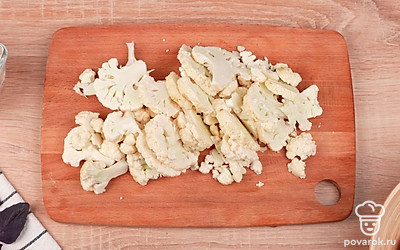 Нарежьте цветную капусту. Нарежьте тонкими пластинками зубчики чеснока.