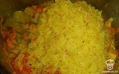 Когда морковь станет мягкой, всыпьте рис. Налейте воду так, чтобы она закрывала содержимое кастрюли на два пальца. Варите плов на среднем огне до готовности. 