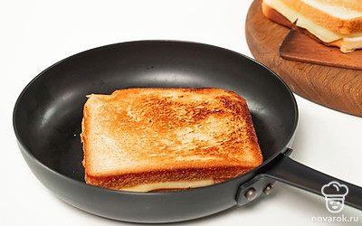 Приготовьте блюдо. Сковороду разогрейте на среднем огне, влейте в нее растительное масло. Выложите тосты, придавливая их сверху грузом. Используйте для этого тарелку и кастрюлю. Через 2-3 минуты переверните тосты другой стороной и обжарьте столько же времени.