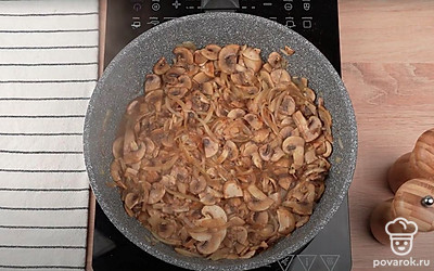 Обжарьте репчатый лук до золотистого цвета и характерного аромата в течение 3-5 минут. Выложите на сковороду нарезанные шампиньоны. Добавьте на сковороду оставшееся сливочное масло и чеснок. Тушите грибы и лук в течение 5-7 минут до готовности шампиньонов.